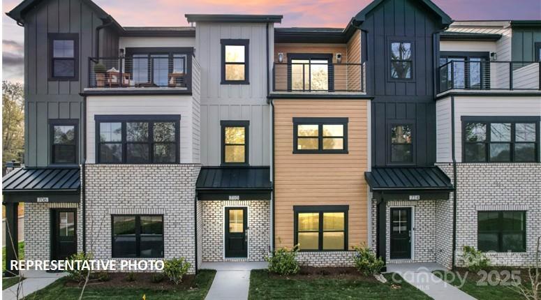 Modern attached townhomes with mixed siding, brick lower levels, and small balconies at dusk.