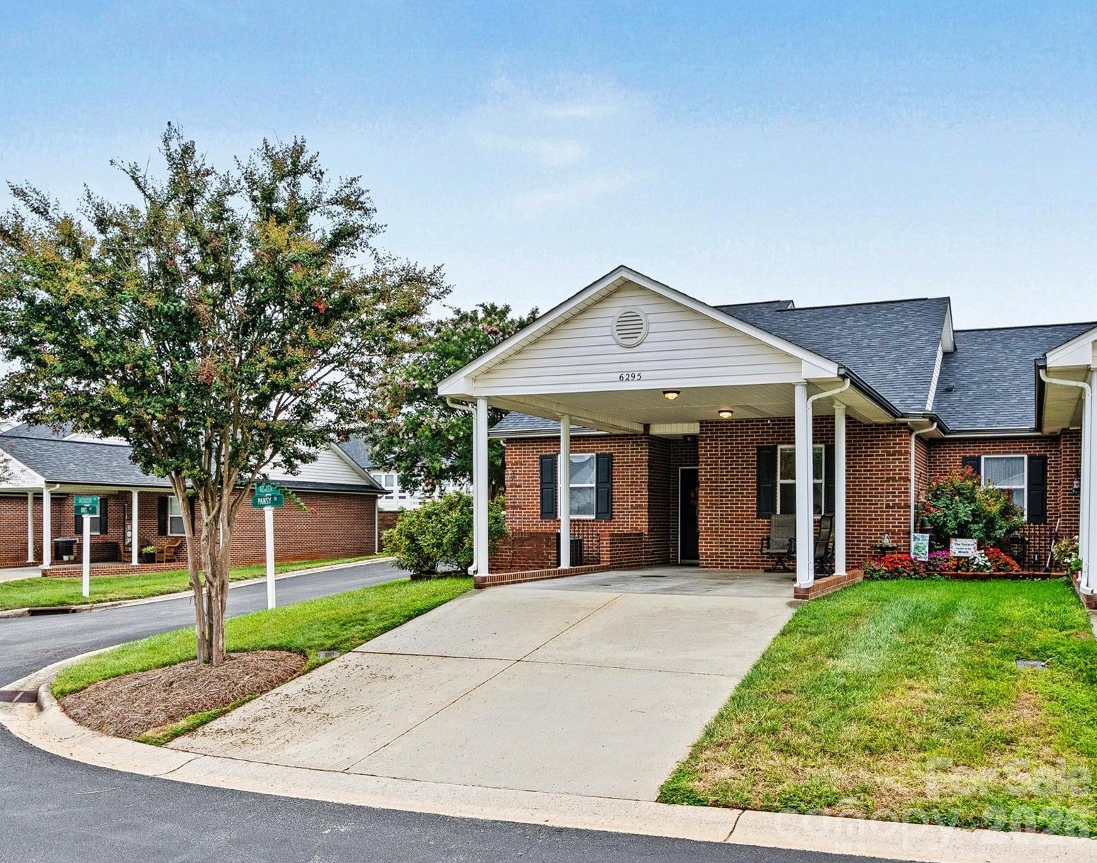 Brick condo building with a covered entrance, white columns, and a broad concrete driveway.