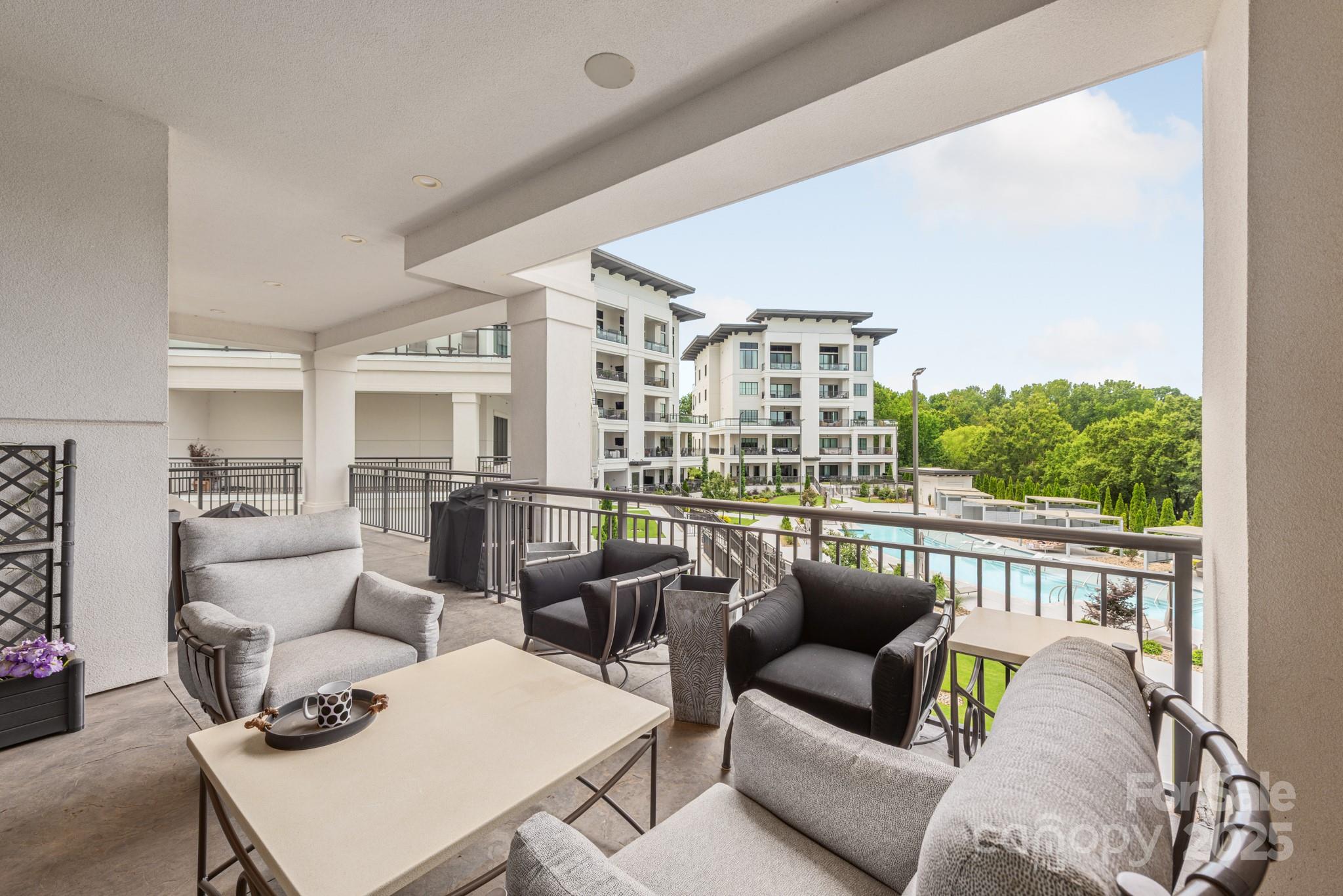 Furnished condo balcony overlooking the community pool and neighboring buildings.