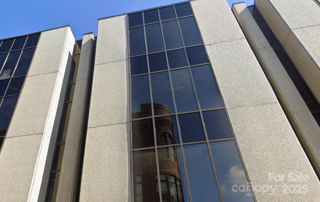 Modern commercial building with reflective glass windows and light concrete panels.