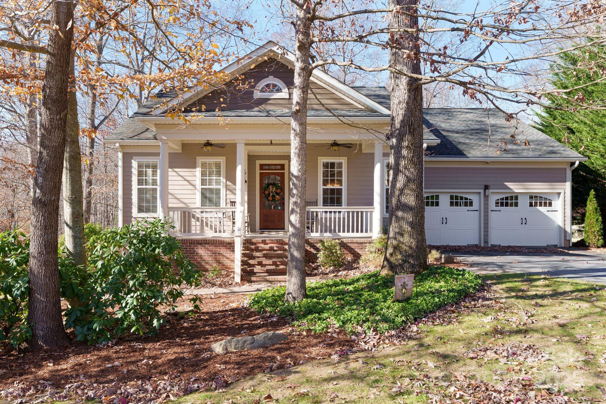 Taupe house with a covered porch and two-car garage framed by mature trees.
