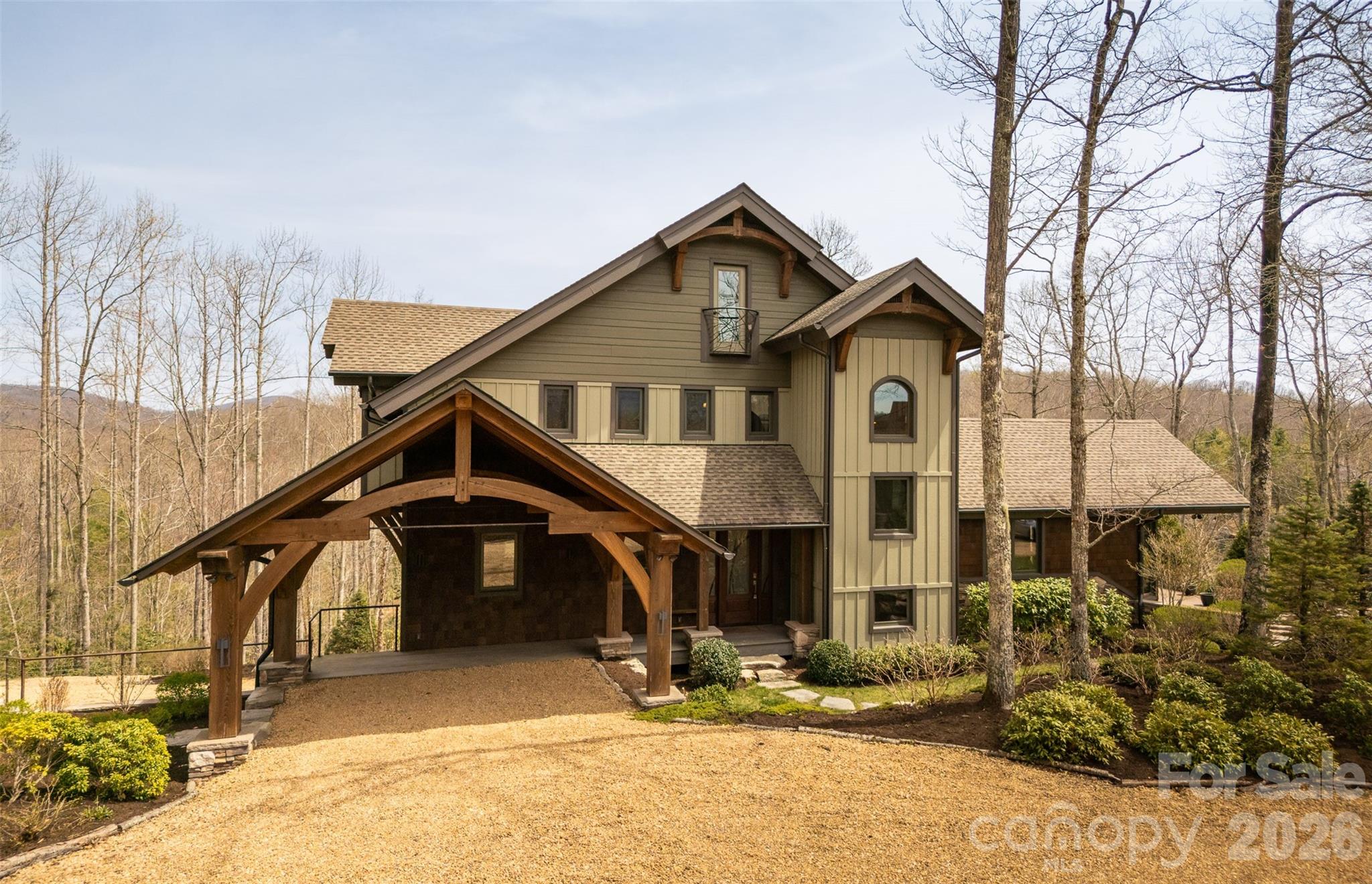 Mountain-style home with a timber-frame porte-cochère and wooded surroundings.