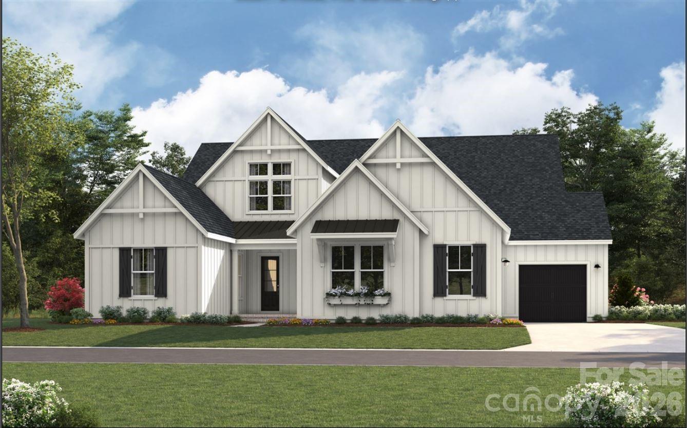 White farmhouse-style home with multiple gables, black shutters, and a landscaped front lawn.
