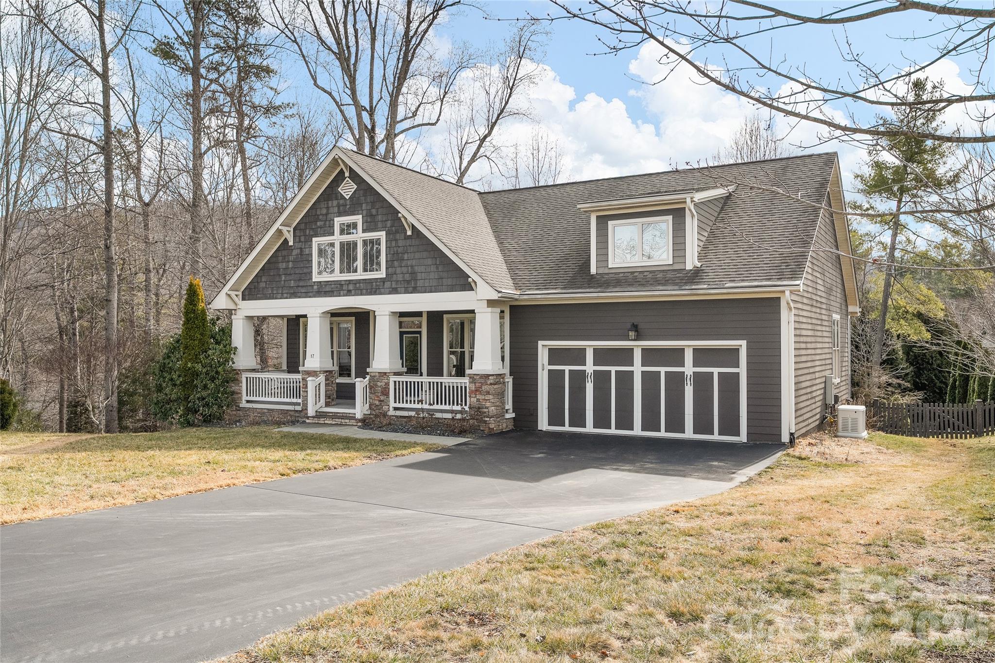 Gray two-story house with a covered porch, stone column bases, and a wide driveway.