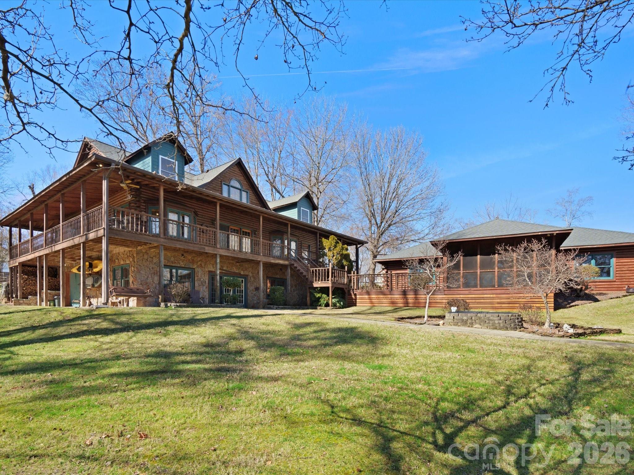Multi-level wood-and-stone home with wraparound decks and a screened porch.