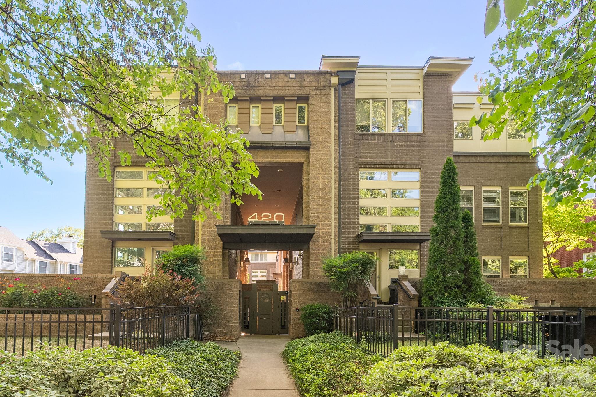 Multi-story brick residential building with a recessed entrance marked 420 and a landscaped, fenced walkway.