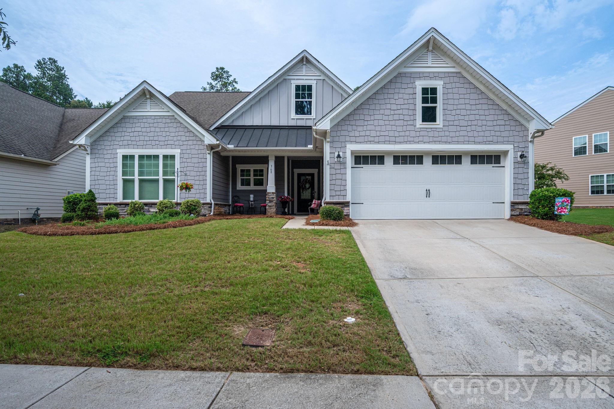 Gray shingle-style home with multiple gables, a covered porch, and a wide two-car garage.