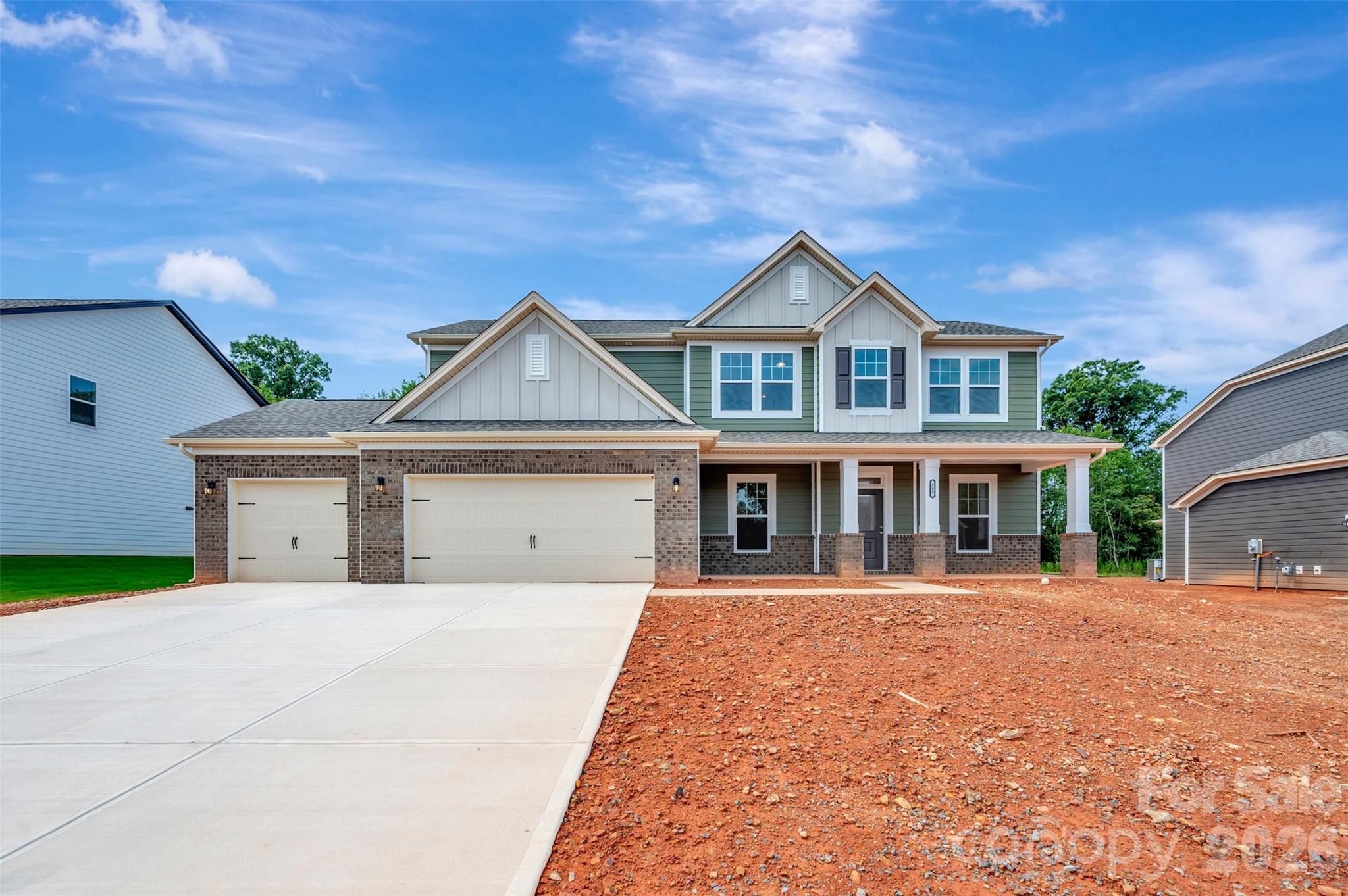 Two-story home with a three-car garage, covered porch, and broad concrete driveway.
