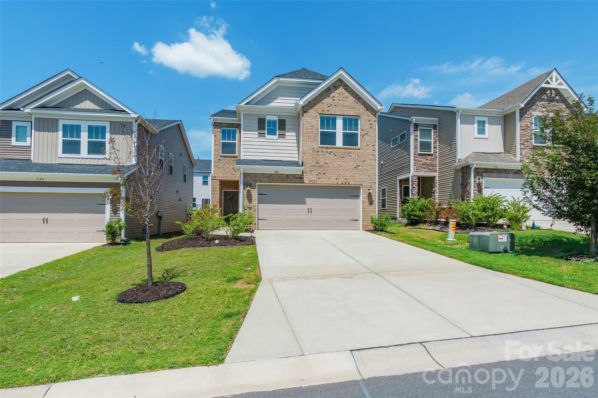 Two-story brick-and-siding home with a double garage, wide driveway, and neighboring houses.