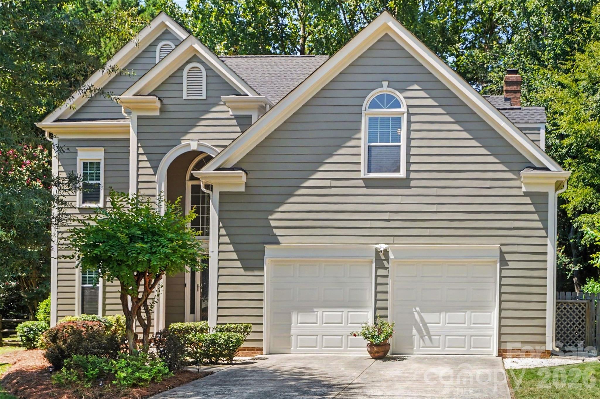Gray two-story house with steep gables, an arched entry, and a double garage.
