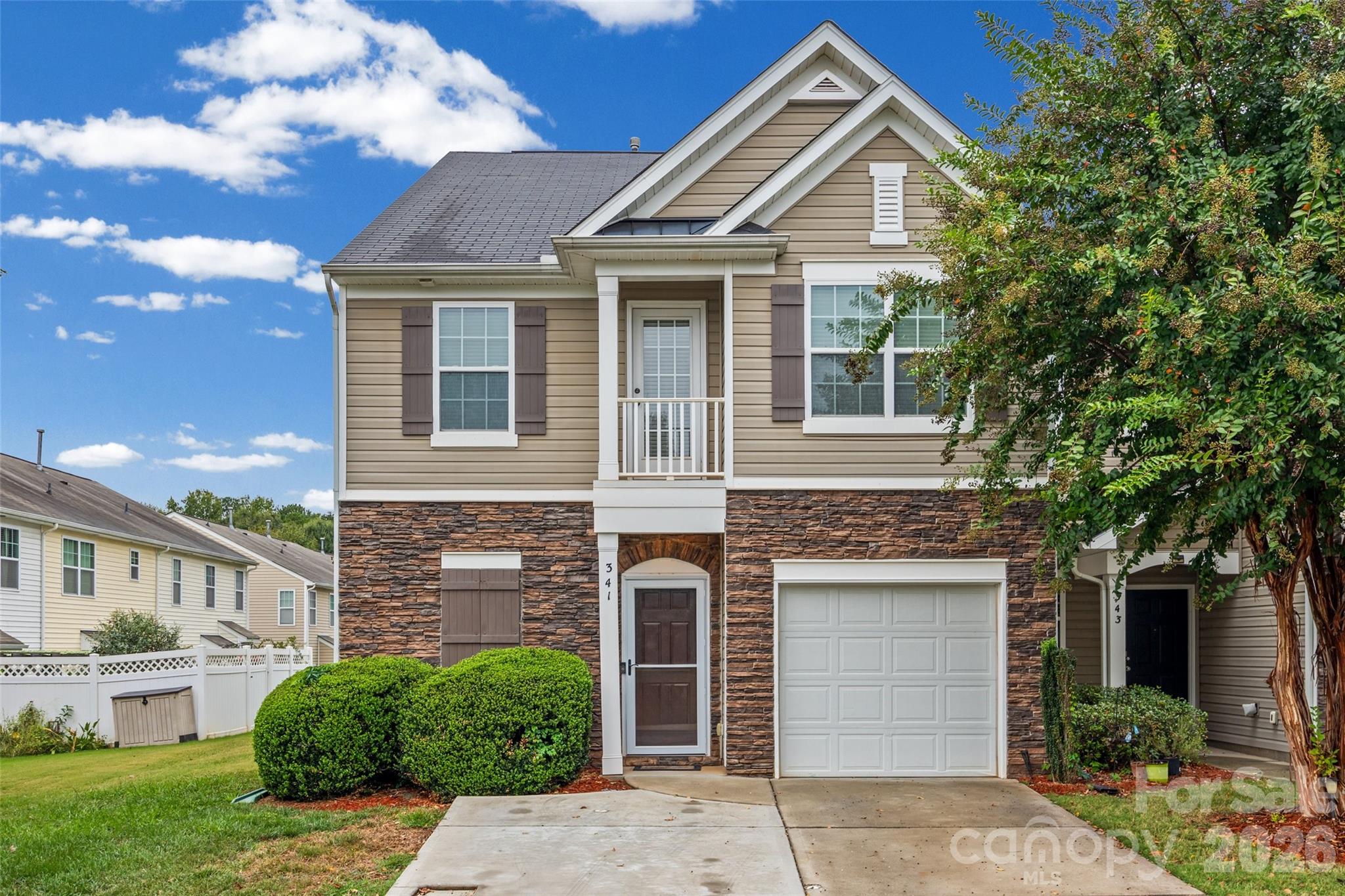 Two-story beige home with stone veneer, a single-car garage, and a small covered entry.