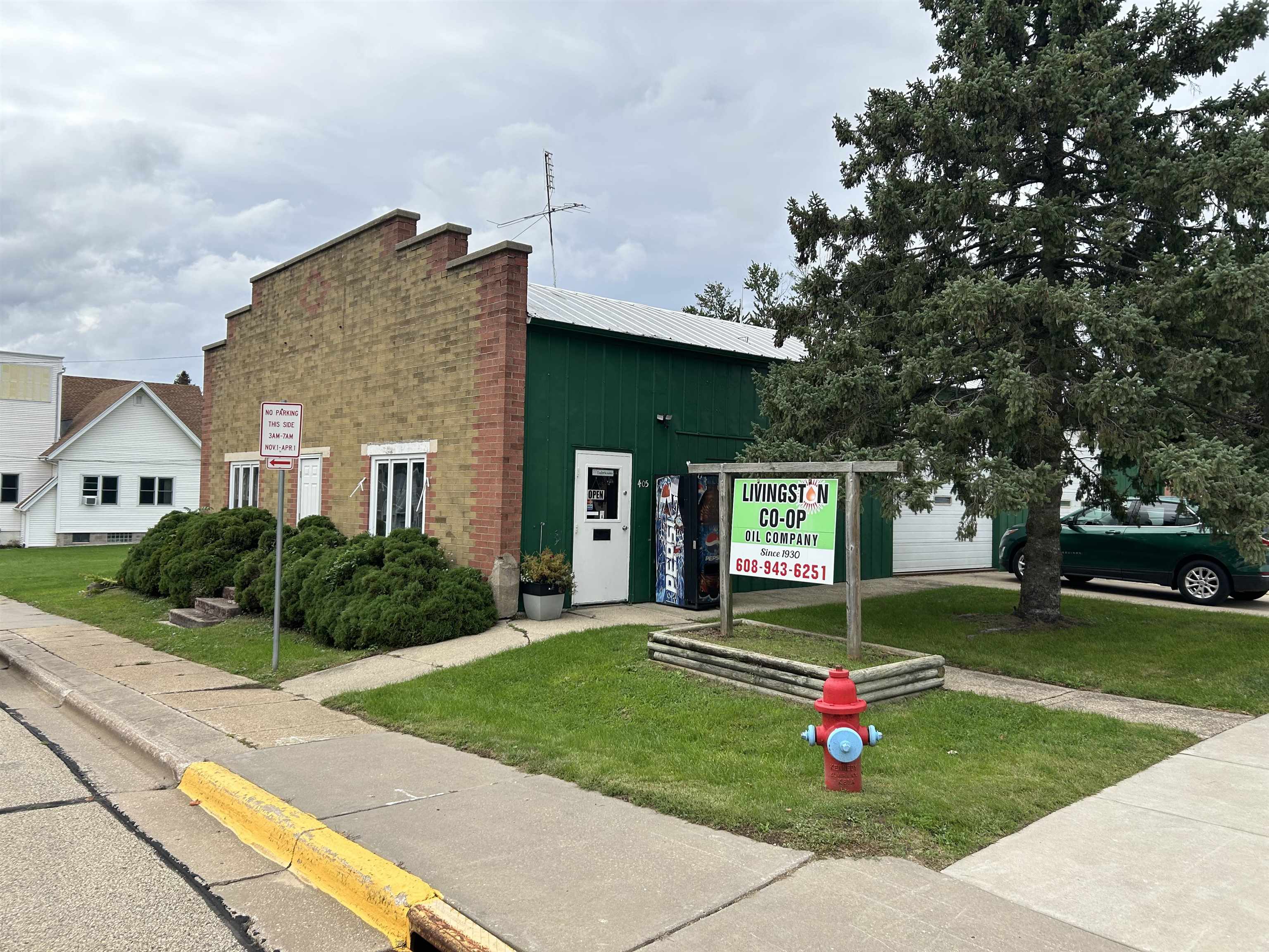 Livingston Co-op Oil Company building with a sign, evergreen tree, and fire hydrant along the sidewalk.