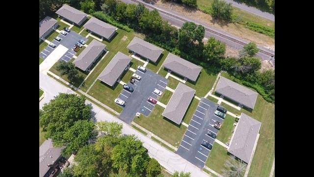 Aerial view of a multi-building complex with parking lots beside railroad tracks.