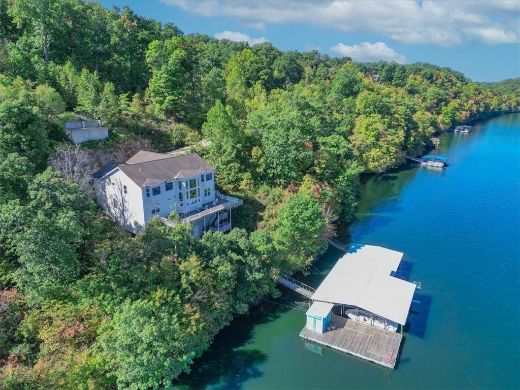 Lakeside home among wooded hills, with a large covered dock over the water.