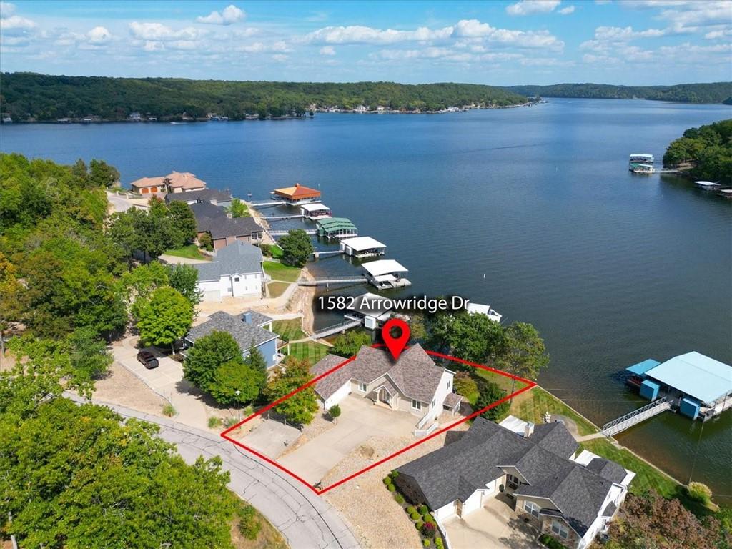 Aerial view of a lakefront home outlined along the shore, with docks and wooded shoreline.