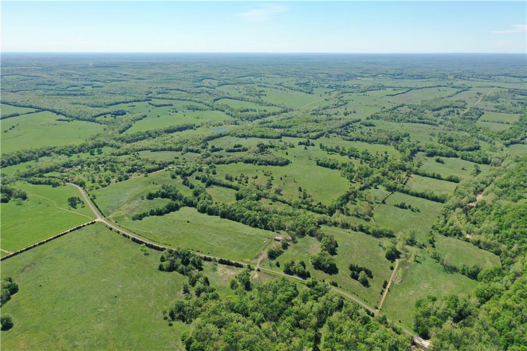 Aerial view of green countryside fields divided by tree lines and country roads.
