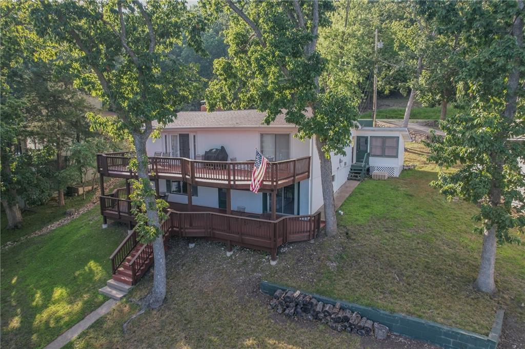 A two-story home among mature trees, with several wooden decks and an American flag.