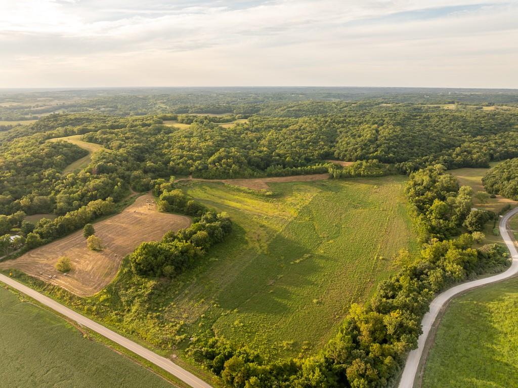Aerial view of rolling farmland, wooded hills, fields, and winding rural roads.