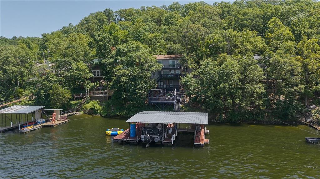 Wooded lakefront homes and covered boat docks seen across the water.