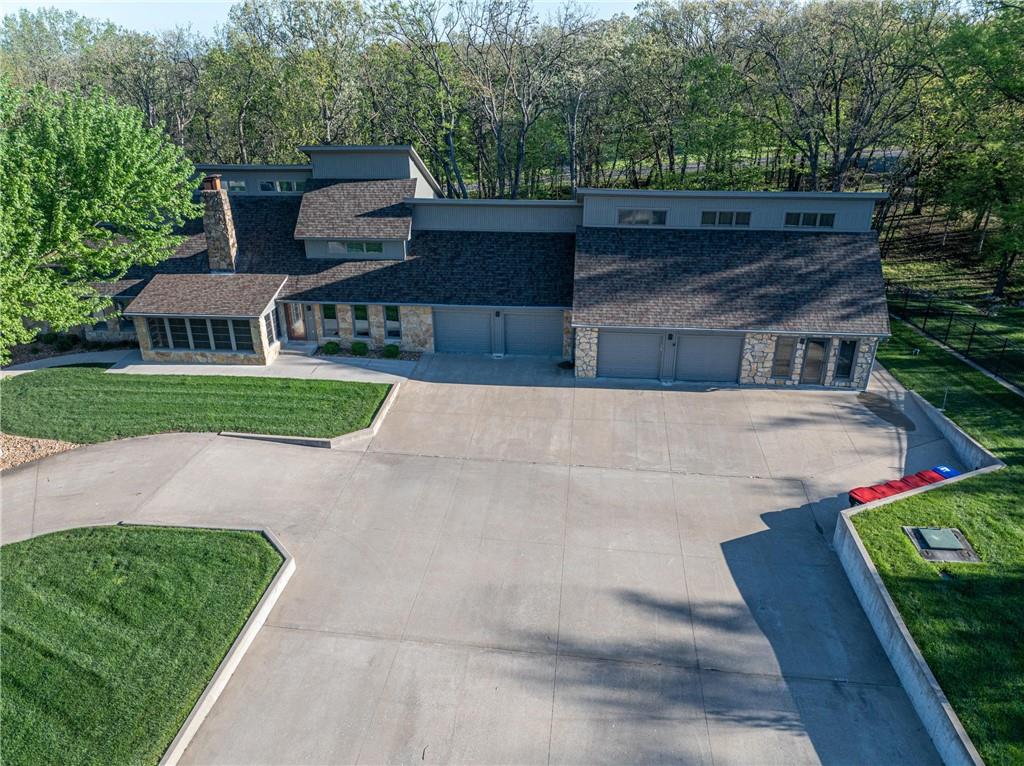 Aerial view of a stone-and-siding home with several garage bays and a broad driveway.