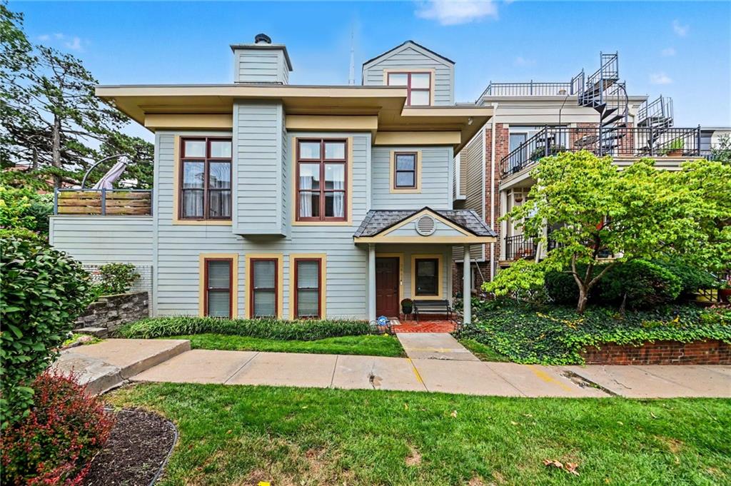 Pale blue two-story home with brown-trimmed windows, a covered entrance, and a landscaped front lawn.