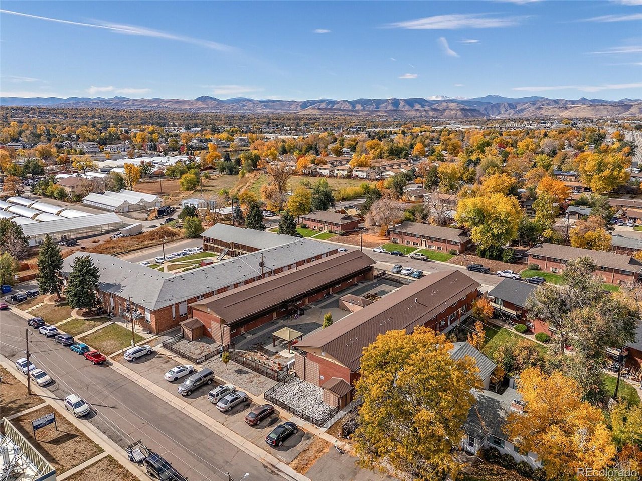 Aerial view of Arvada homes and streets, with golden autumn trees and foothills on the horizon.
