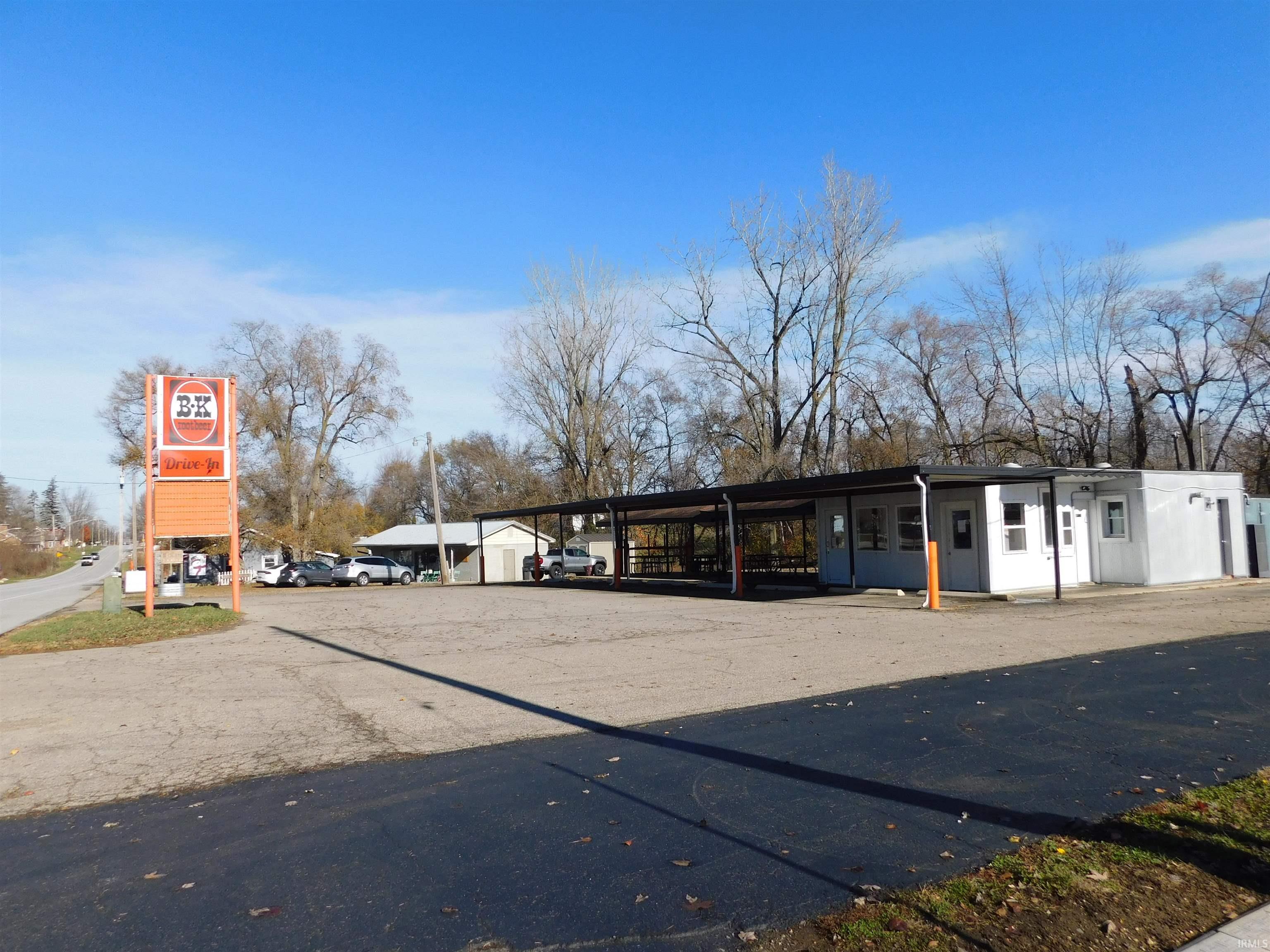 White drive-in restaurant with a covered service area and tall B&K Root Beer sign.
