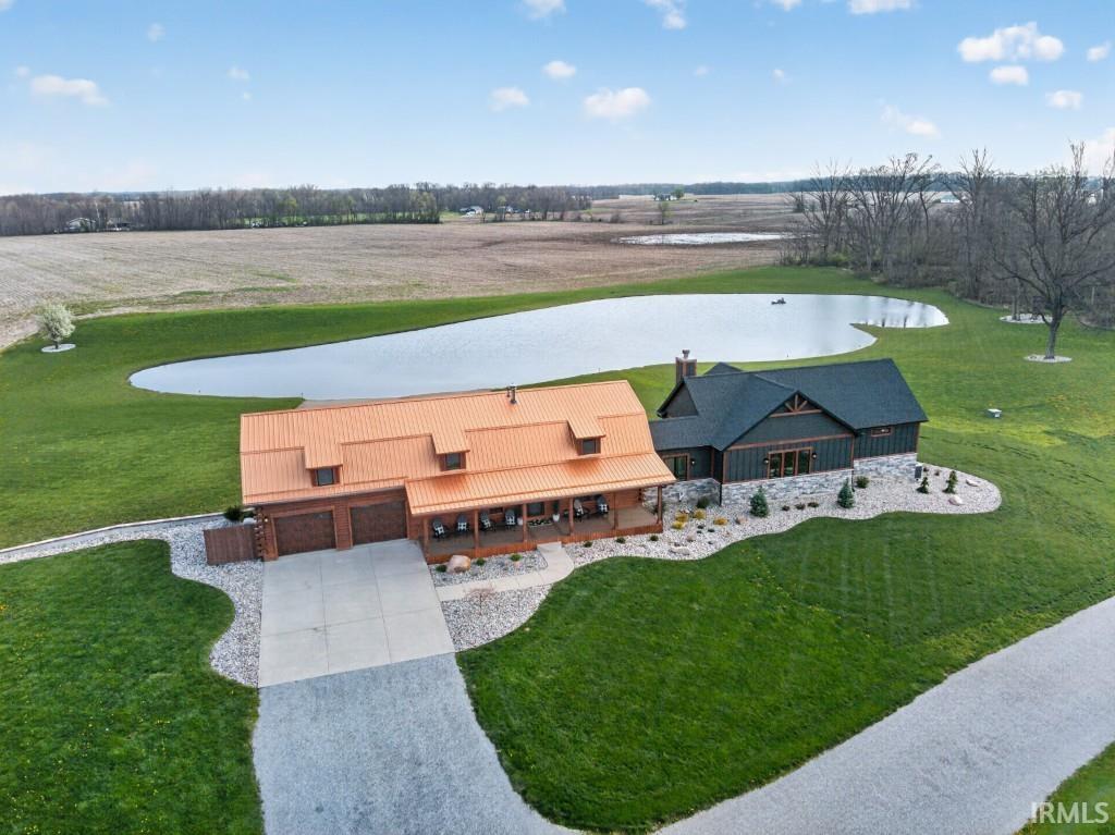 Aerial view of a property with a large building beside a pond and open fields.