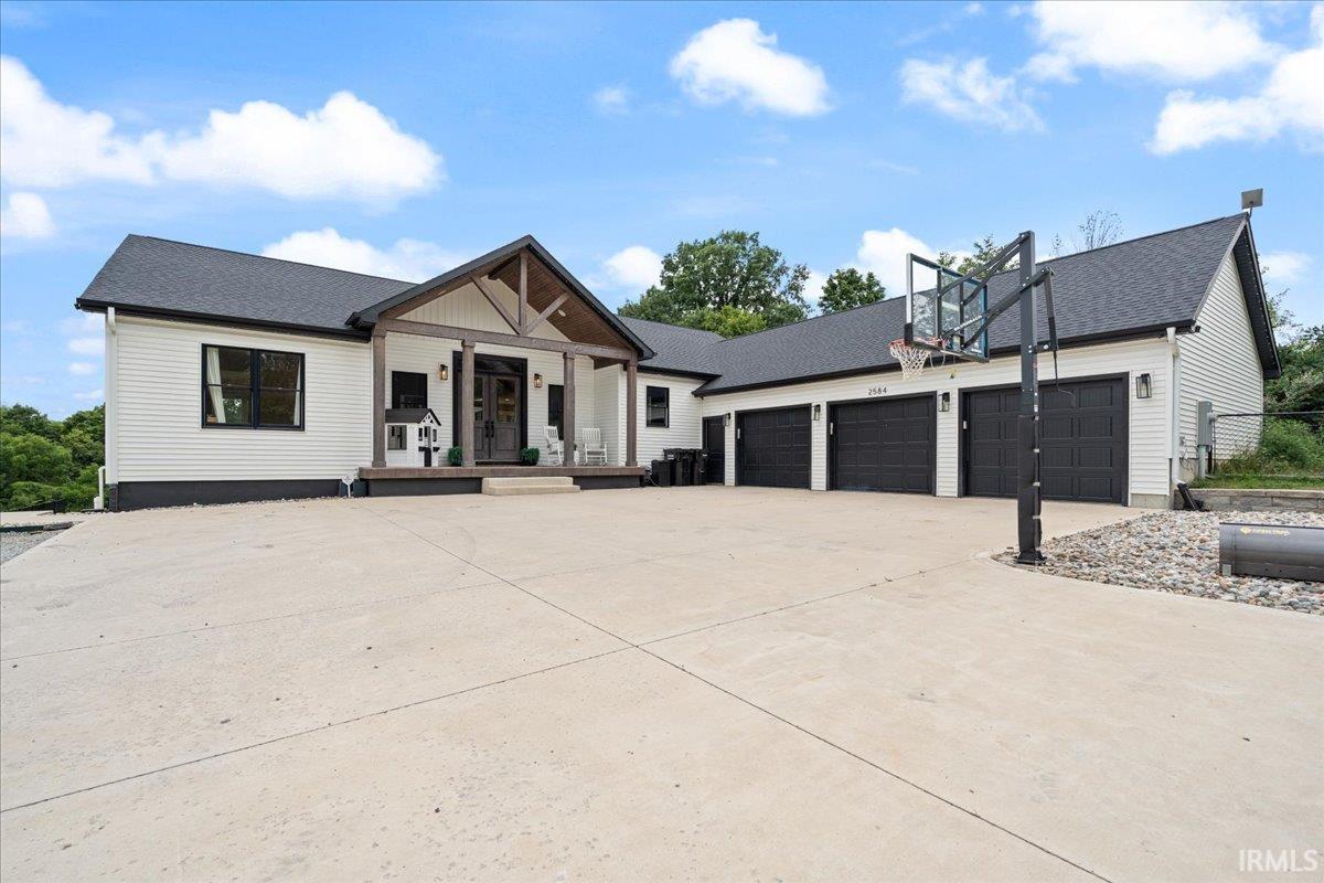 White single-story home with a covered porch, three-car garage, and basketball hoop beside the driveway.