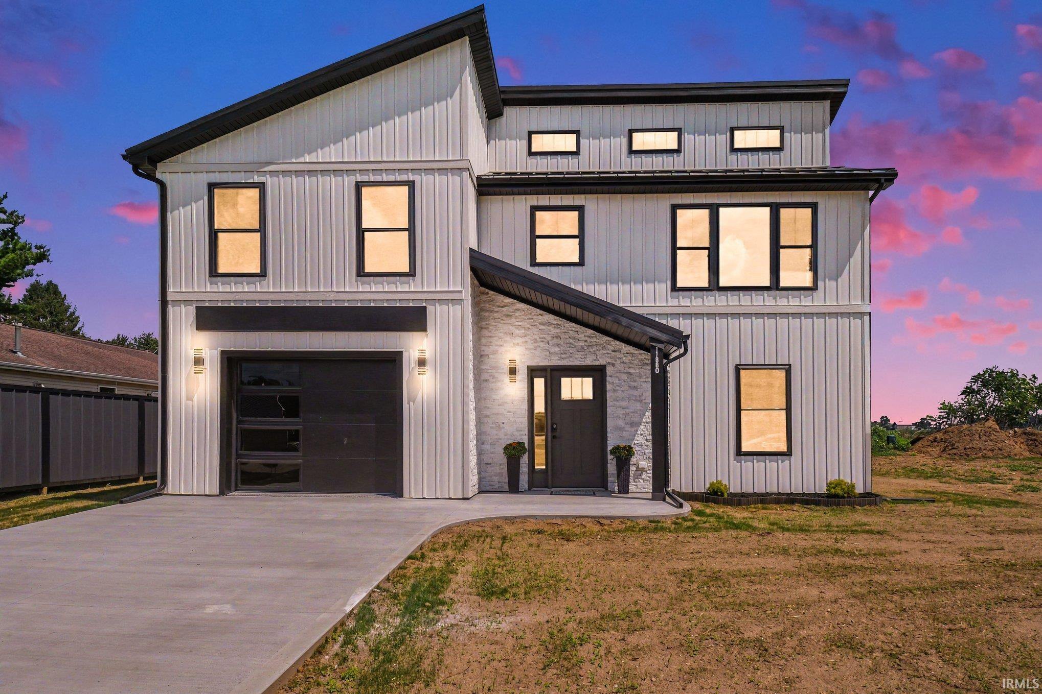 Two-story white home with dark trim, stone entry, and attached garage at dusk.