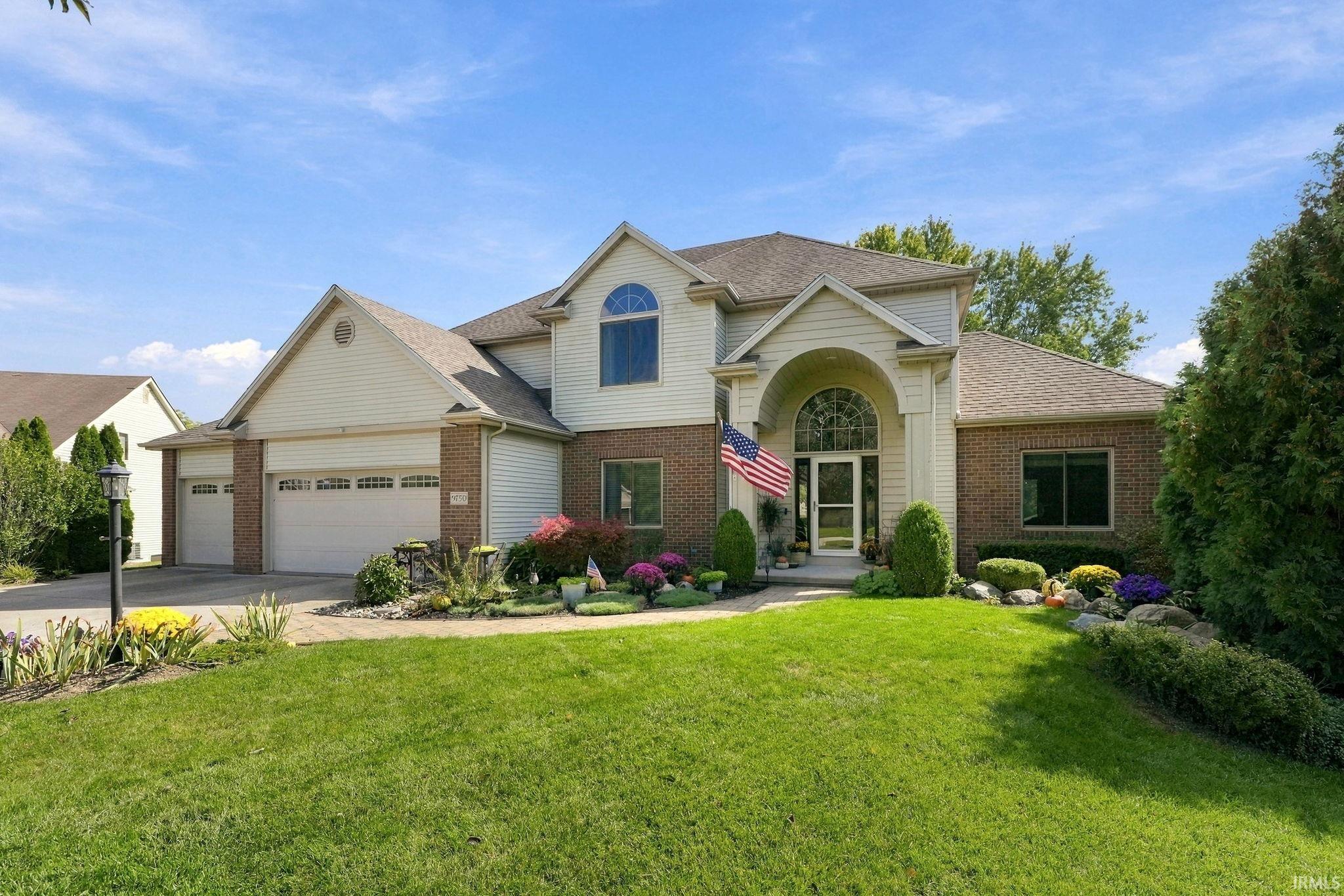 Two-story suburban home with brick-and-siding exterior, arched entry, double garage, and landscaped front lawn.