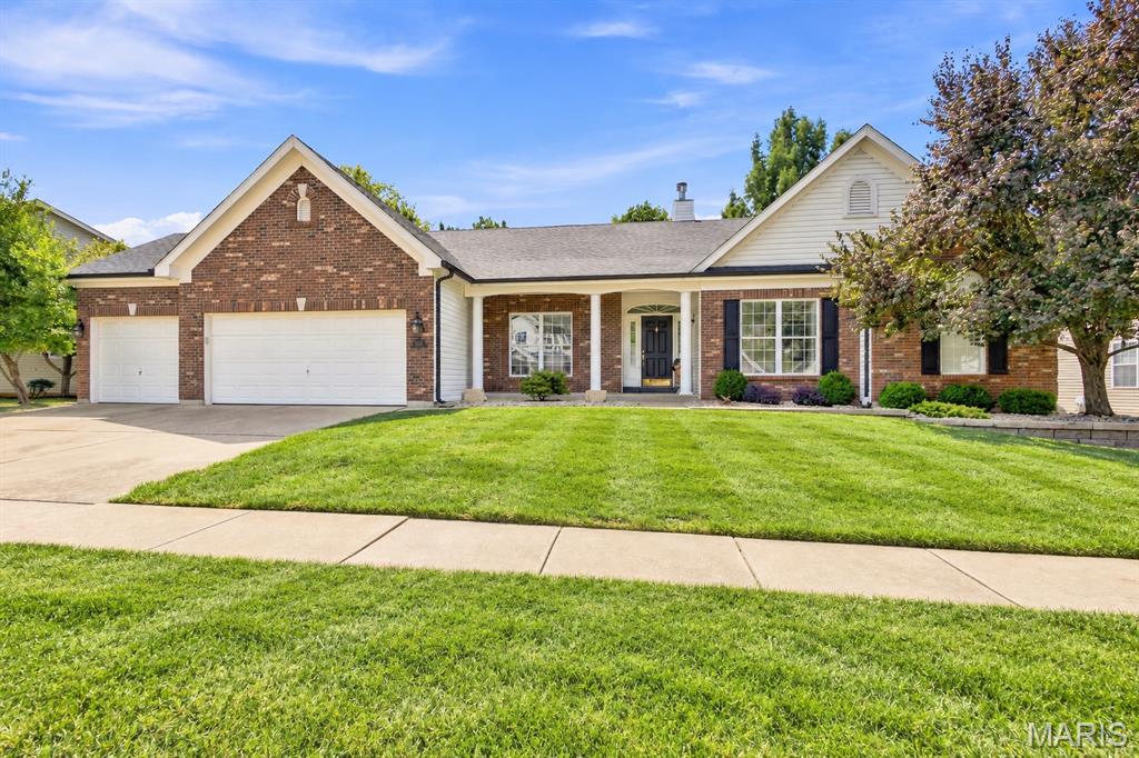 Brick ranch home with two garage doors, a covered porch, and a broad green lawn.