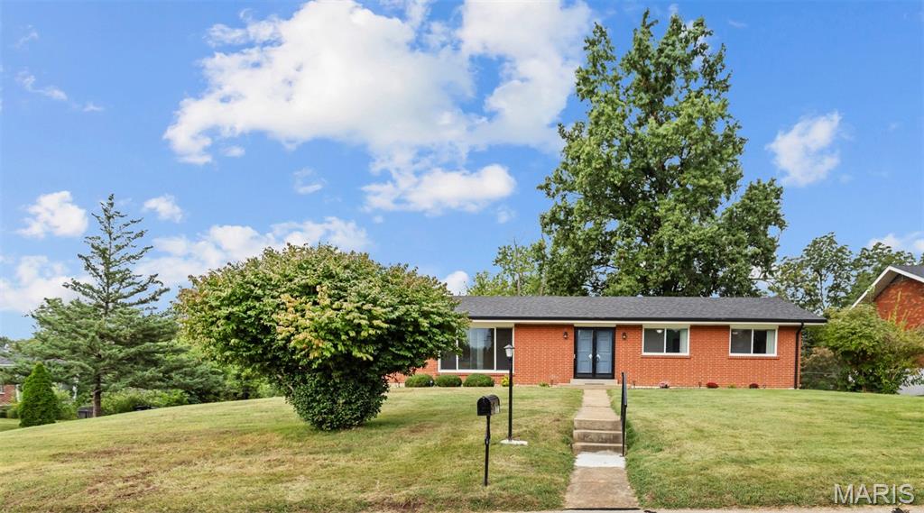 Red brick ranch house with a sloping front lawn, walkway, and mature trees.