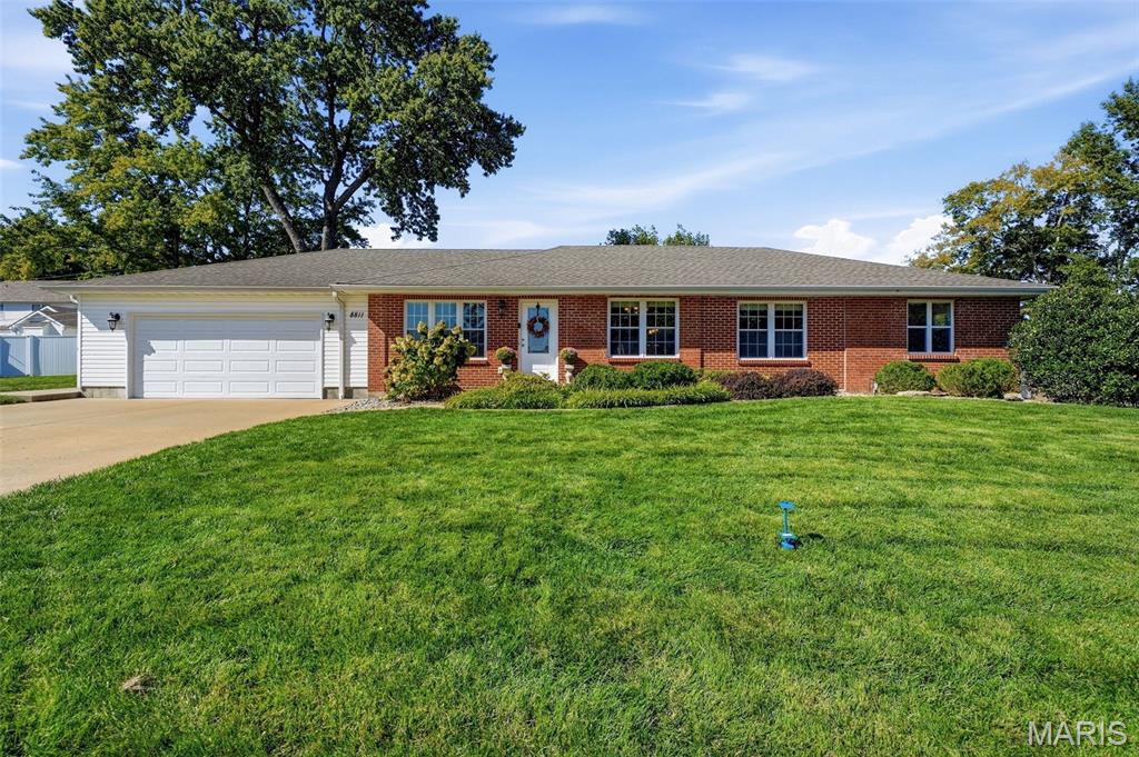 Brick ranch house with an attached two-car garage, broad lawn, and mature trees.