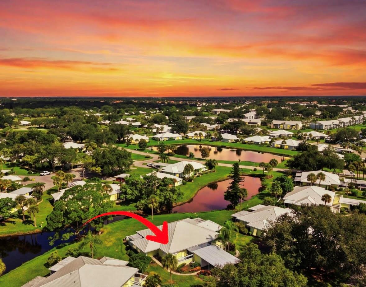 Aerial view of homes and ponds at Plantation Golf & County Club, with a red arrow pointing to a house.