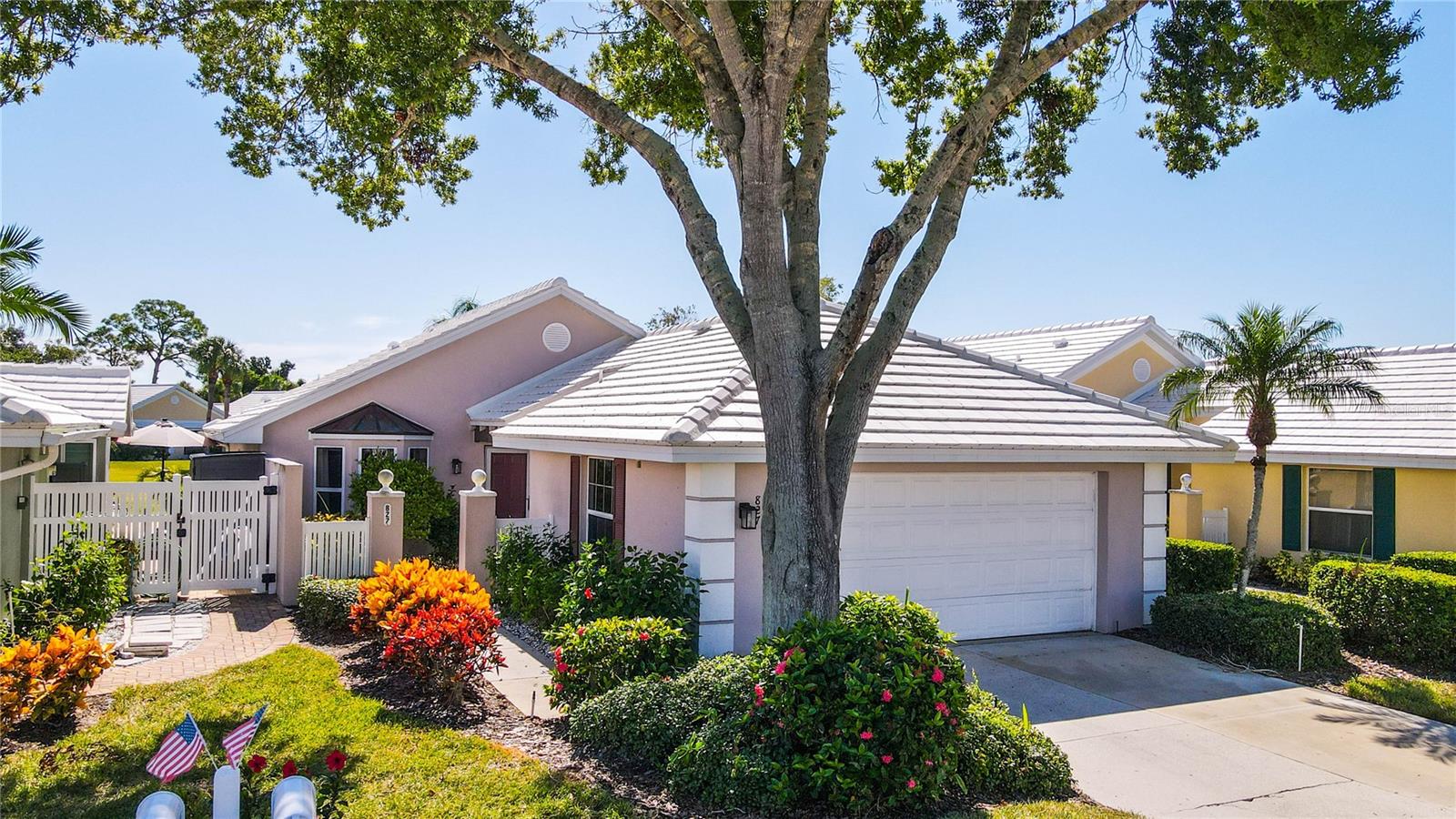 Single-story home with a tile roof and two-car garage beneath a large shade tree.