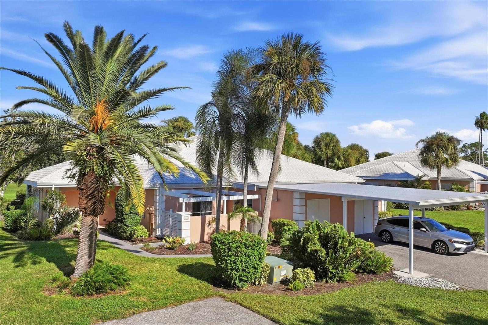 Single-story homes with covered parking, palm trees, and landscaped lawns at Plantation Golf & Country Club.