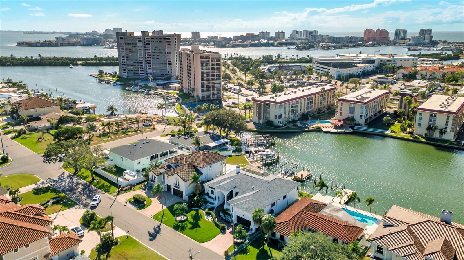 Aerial view of Island Estates waterfront homes and condominiums beside canals, with Clearwater’s skyline in the distance.