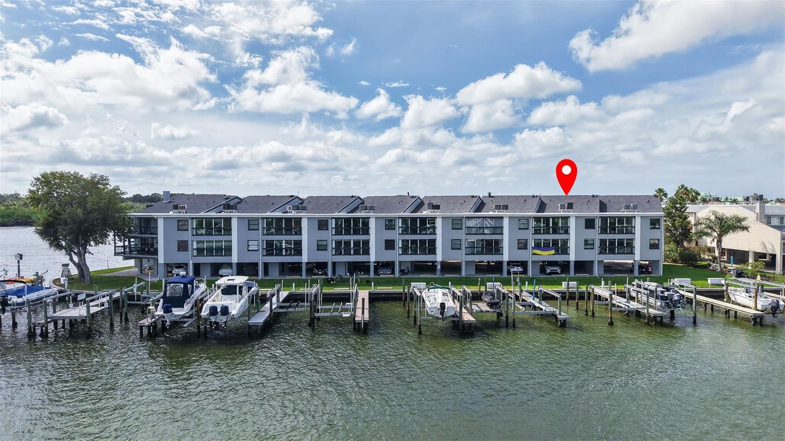 Waterfront condominium building with boat docks and boats along the shore.