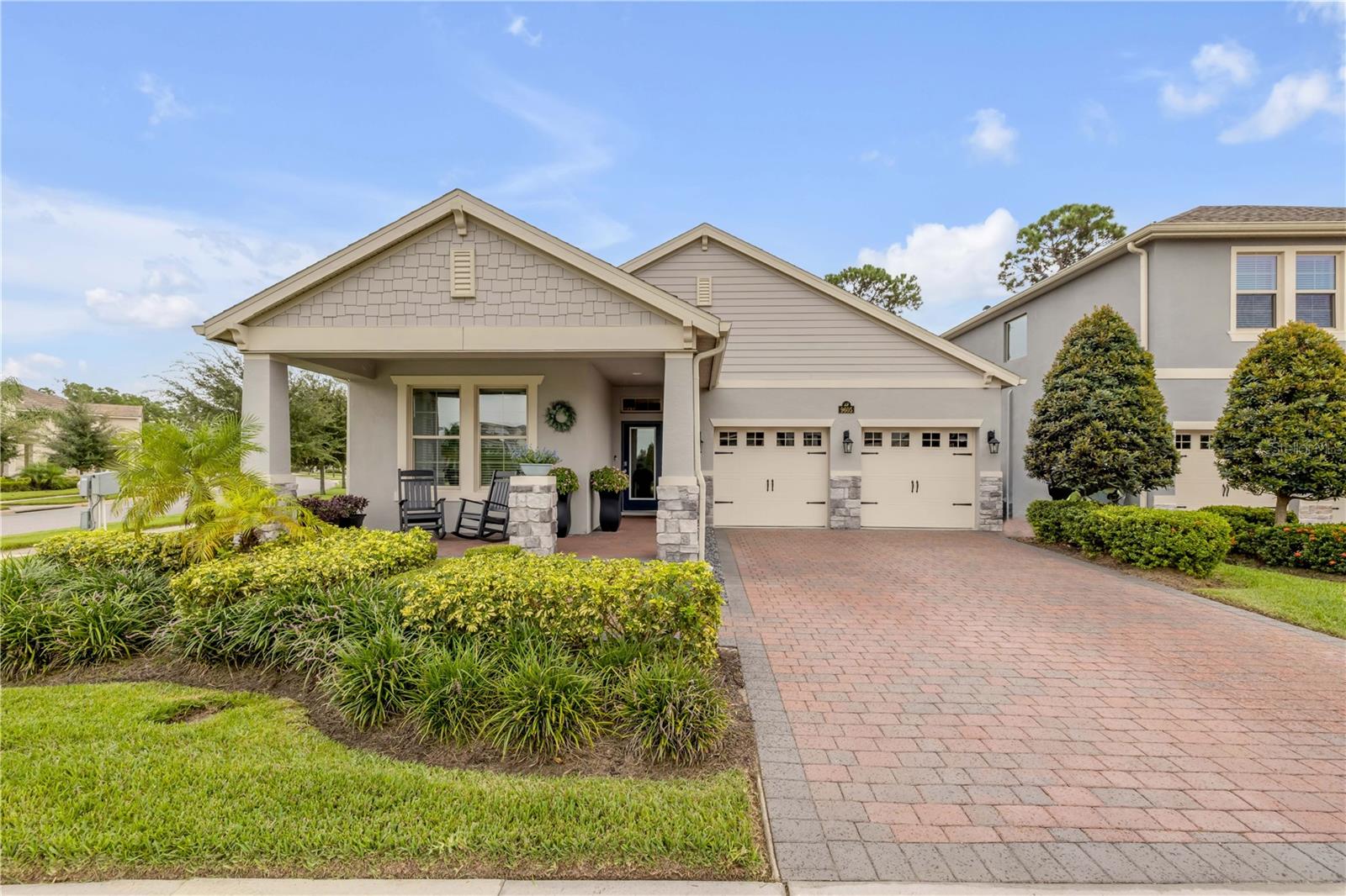 Single-story home with a covered porch, two-car garage, and brick-paver driveway.