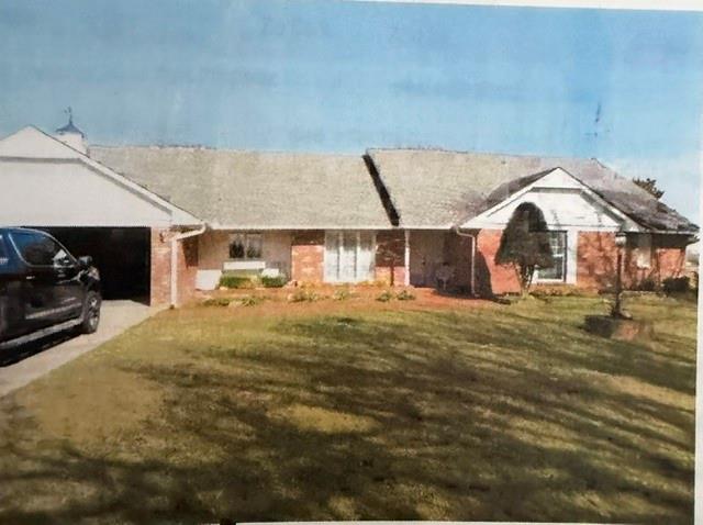Single-story brick ranch house with an attached garage and broad front lawn.