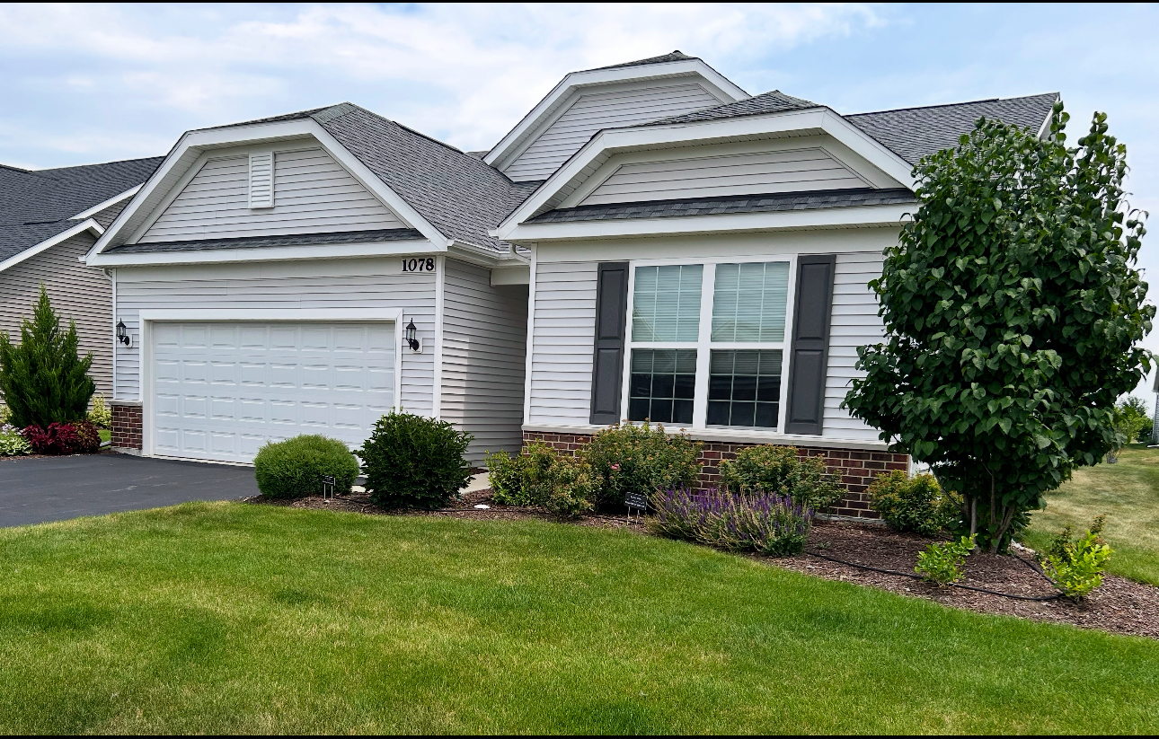 White single-story home with a two-car garage, landscaped flower beds, and the number 1078 above the garage.