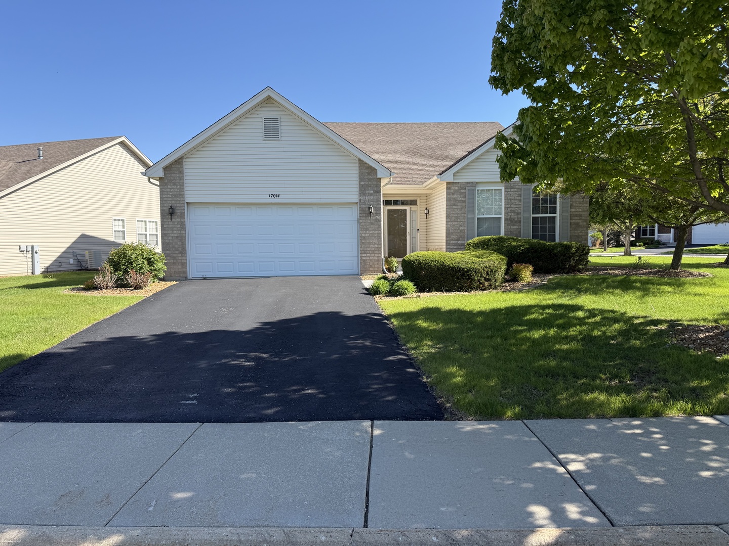 Single-story home with brick accents, a two-car garage, and a shaded, landscaped lawn.