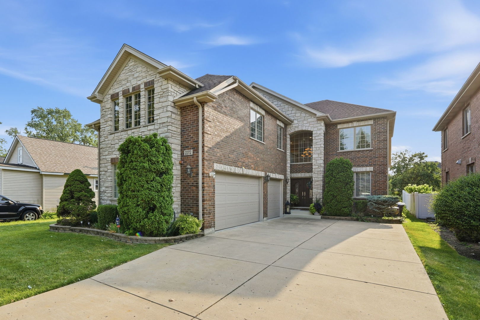 Two-story brick and stone house with a two-car garage and landscaped front yard.