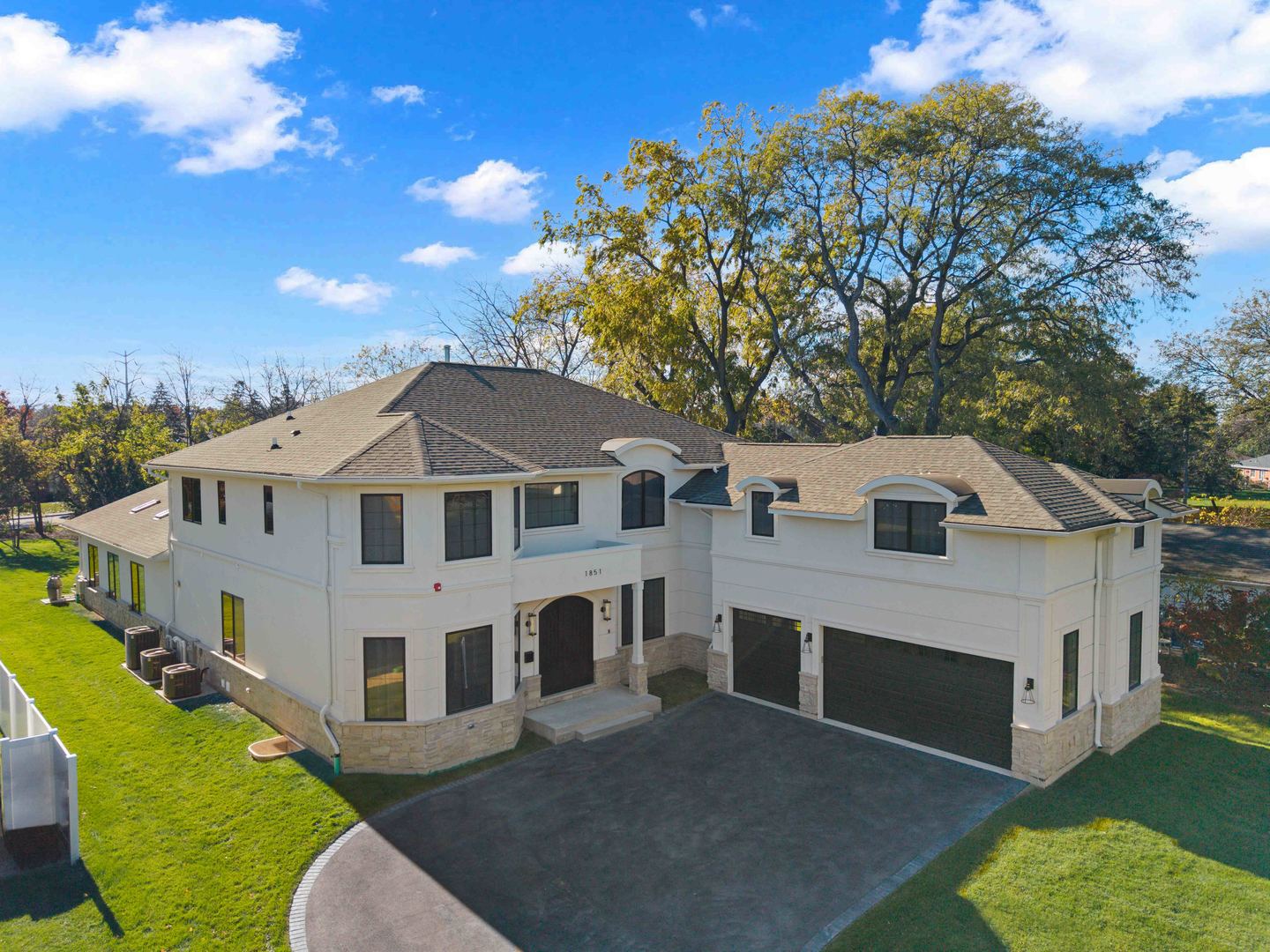 Aerial view of a large white two-story home with an attached garage and curved driveway.