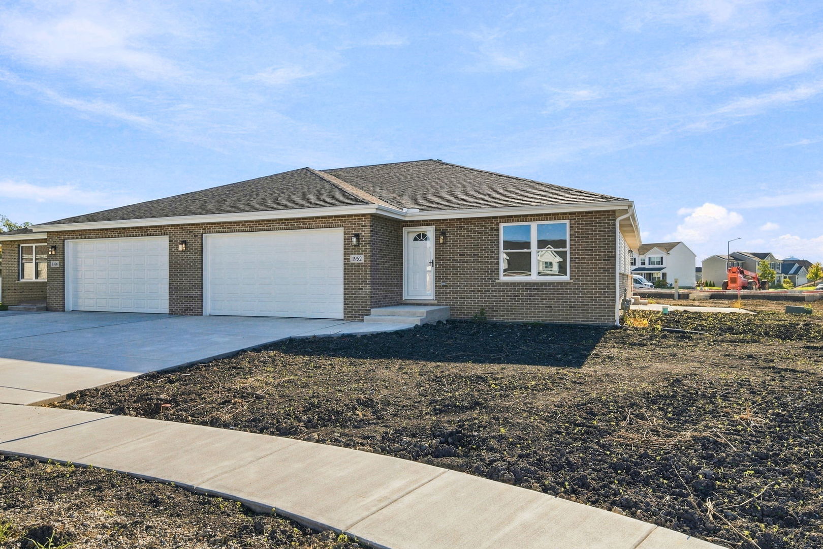Single-story brick home with two garage doors, a concrete driveway, and a mostly bare front yard.