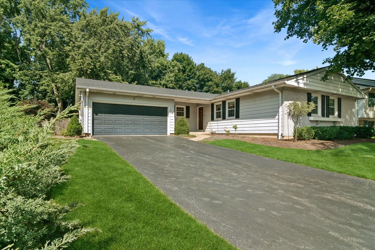 Single-story ranch home with an attached two-car garage, wide driveway, and landscaped lawn.