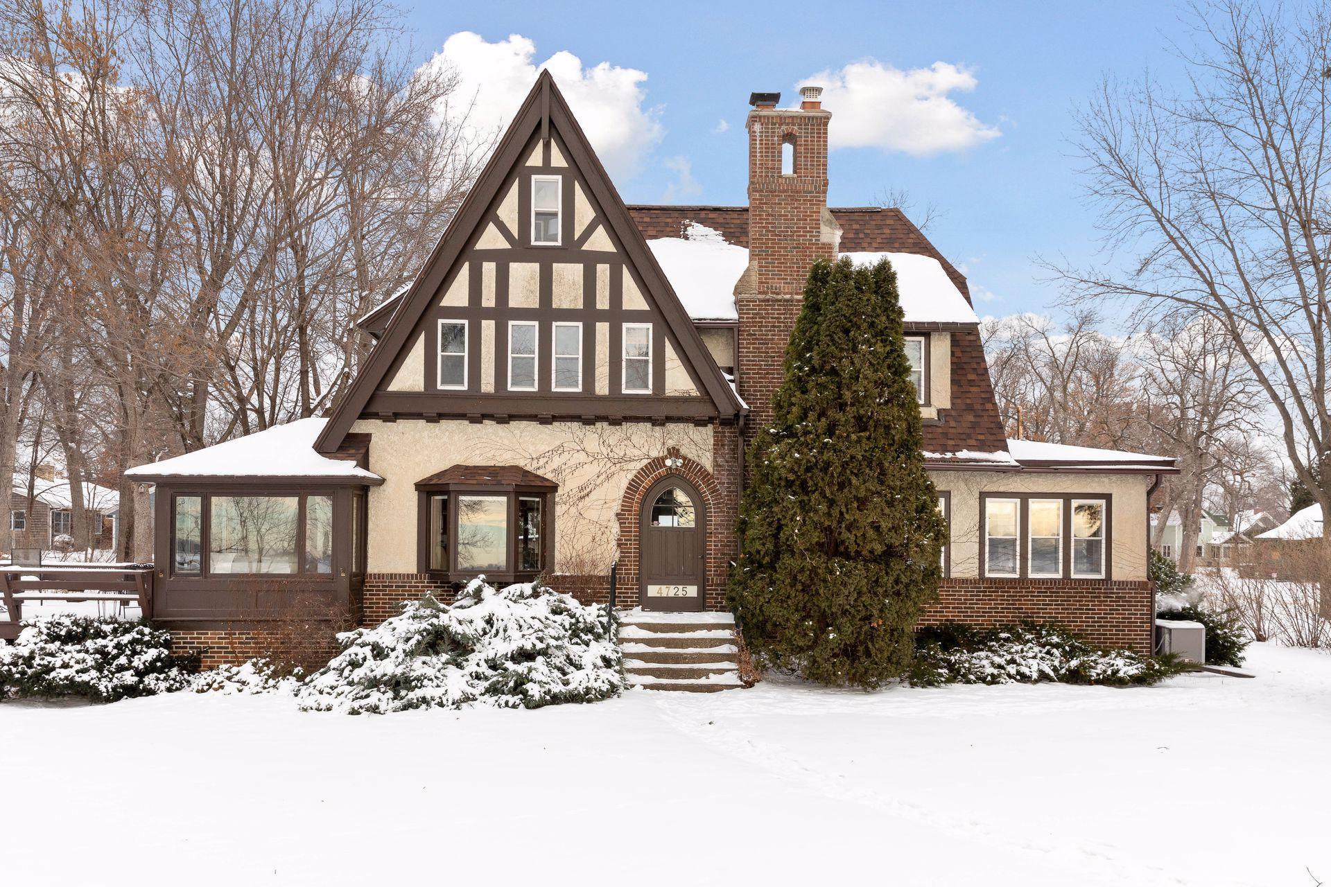 Tudor-style house with a brick chimney and snow-covered front yard.