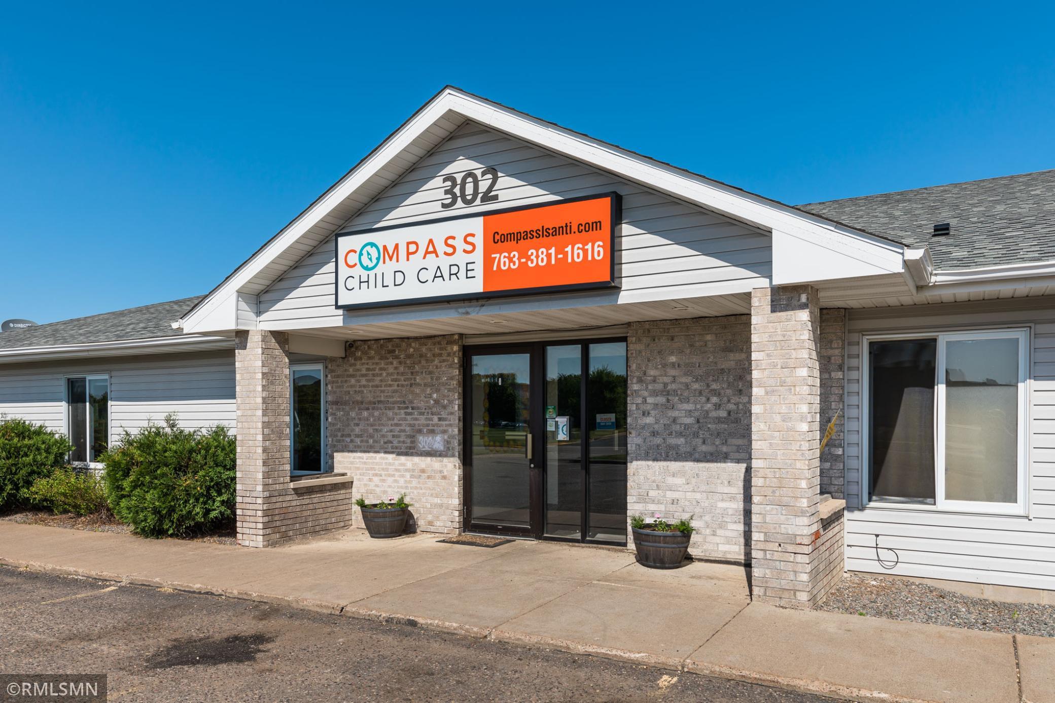 Compass Child Care building with a large orange-and-white sign above its brick entrance.