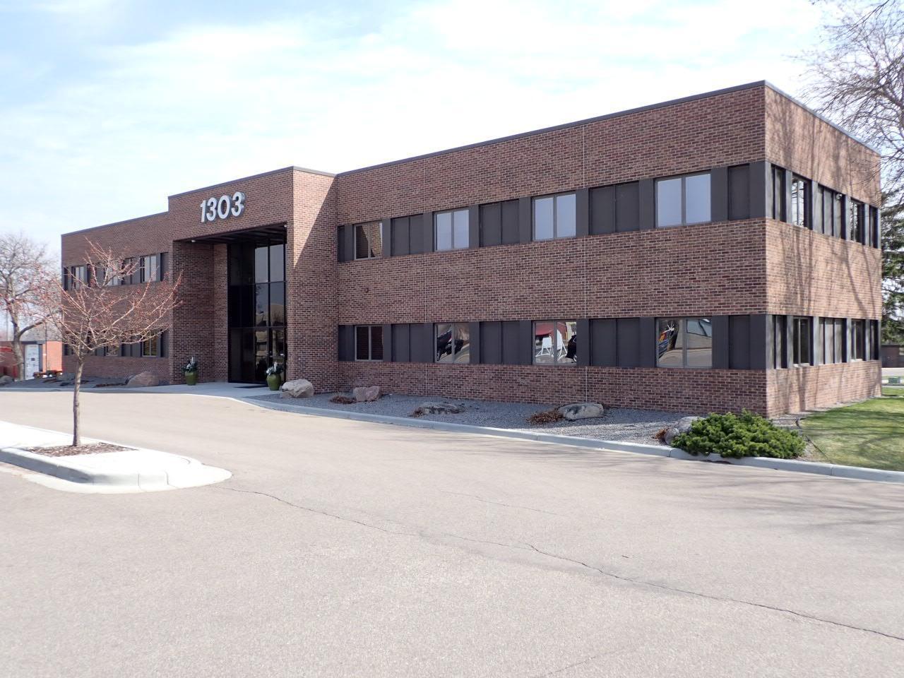 Two-story brick office building with dark horizontal windows and entrance marked 1303.